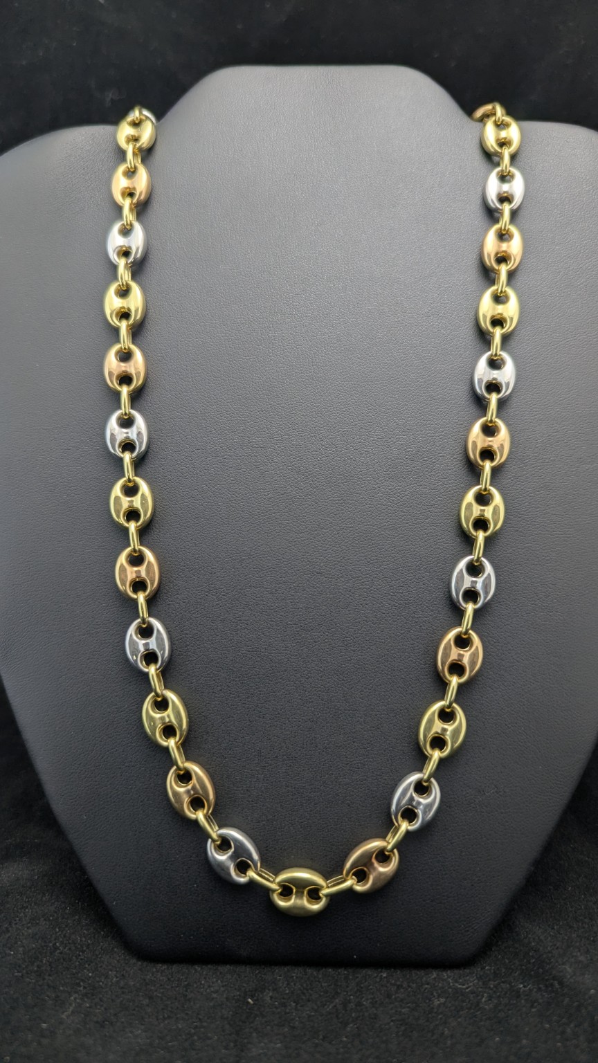 22-inch 14K tri-color Gucci-link chain with alternating yellow, white and rose gold links on a dark jewelry display
