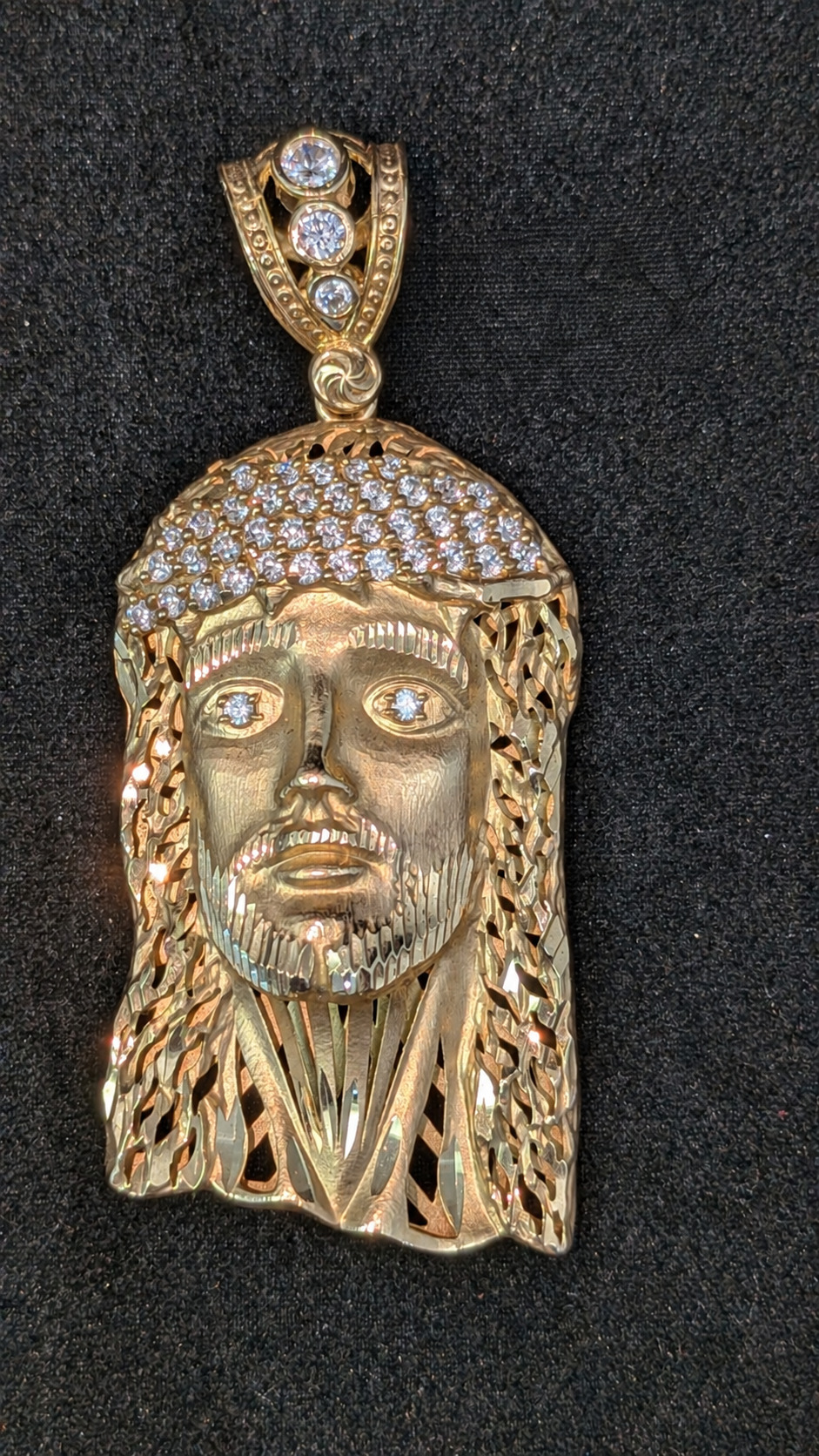 Front of 14K yellow gold Jesus head pendant with stone accents on the crown, eyes and bail