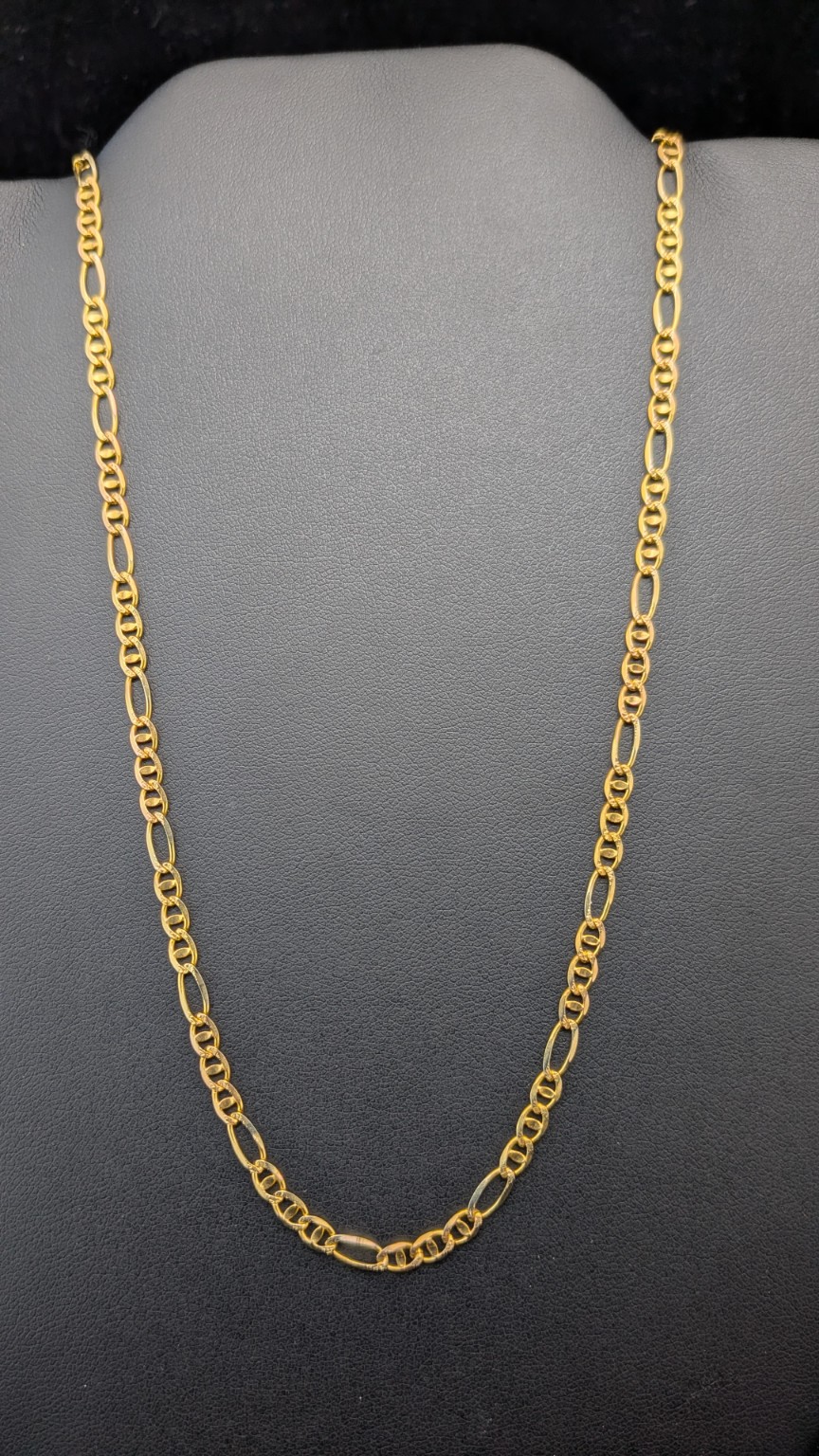 Full 22-inch 14K yellow gold Figaro chain on a jewelry display