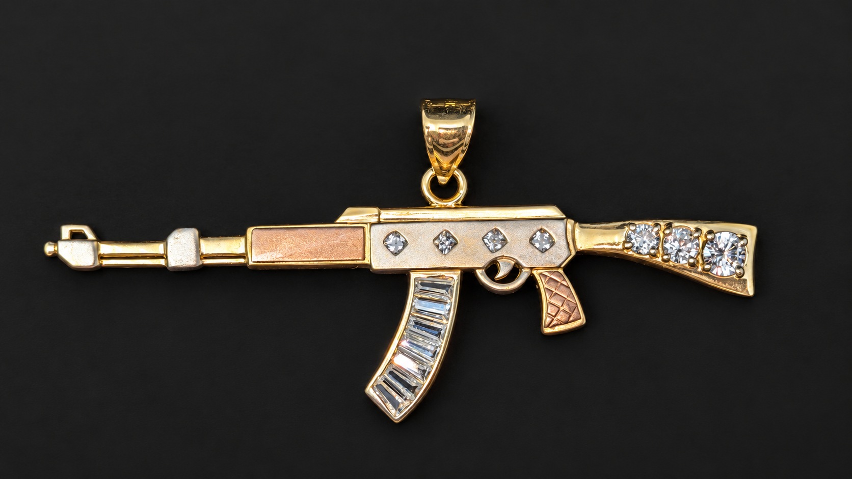Front of the 14K yellow gold AK-style pendant with clear stone accents and rose-tone details on a smooth dark background