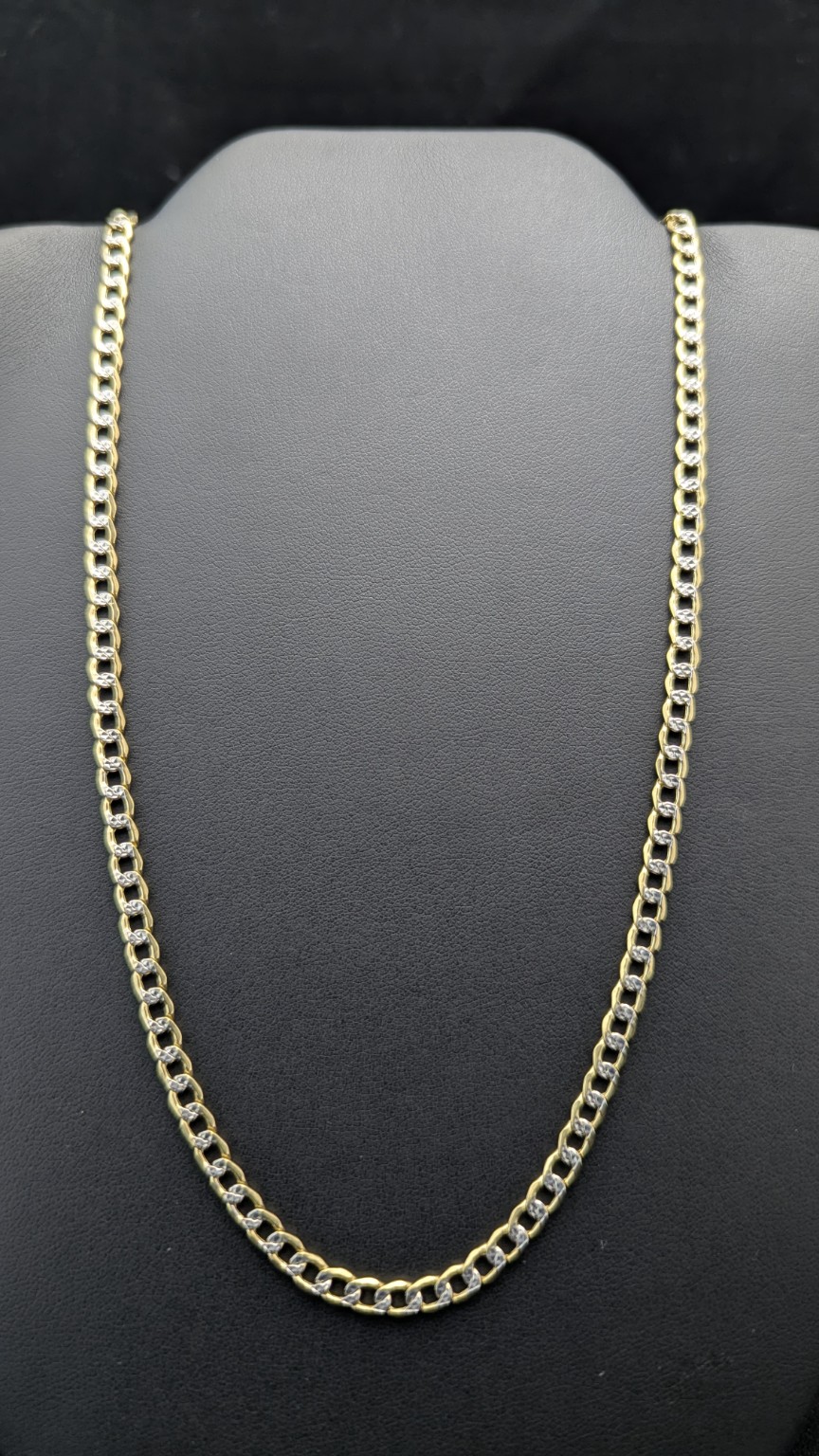 24-inch yellow gold curb chain with bright white accents on a dark jewelry display